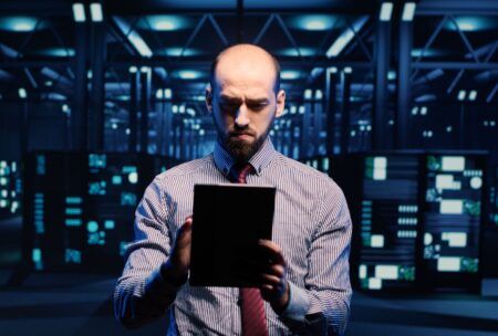 a man dressed in a suit is holding a tablet, concentrating on daily management duties