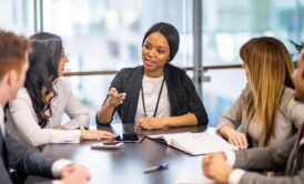 a woman in a business suit engages in discussion with her team, emphasizing the disciplines of execution in their conversation