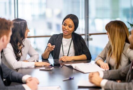 a woman in a business suit engages in discussion with her team, emphasizing the disciplines of execution in their conversation