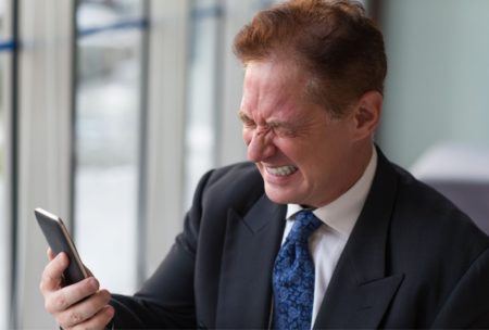 a businessman in suit checking phone, likely participating in online anger management course