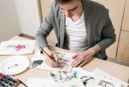 a man focused on his art at a table, learning how to become a freelance artist