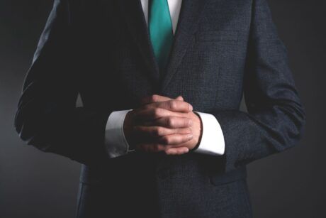 a man in a suit and tie, with hands folded, represents the essence of leadership lessons and authority