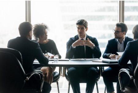 A group of business professionals discussing operating cadence around a conference table.