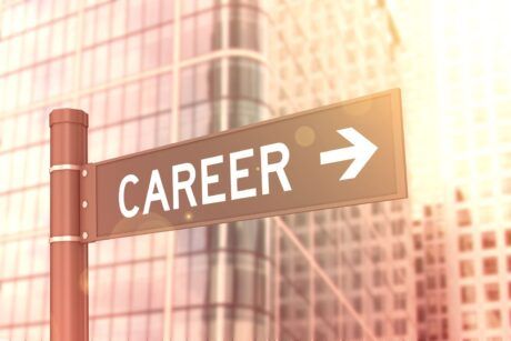 A street sign directing towards career opportunities in front of a building, inspiring you to reinvent your career path.