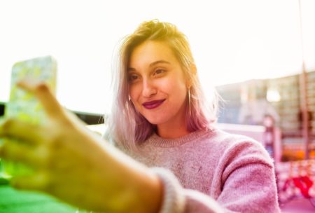 A woman captures a selfie with her phone, showcasing the use of Snapchat for Business