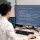 a man at a desk with a computer screen and keyboard, concentrating on a Tailwind CSS crash course