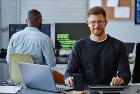 a man at a desk using a laptop and computer, focused on learning terraform for beginners
