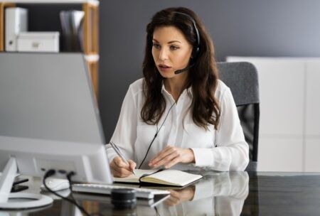 A woman in a headset sits at a desk, engaged in virtual assistant online training