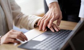 Two professionals on a laptop, highlighting the importance of workplace harassment prevention.